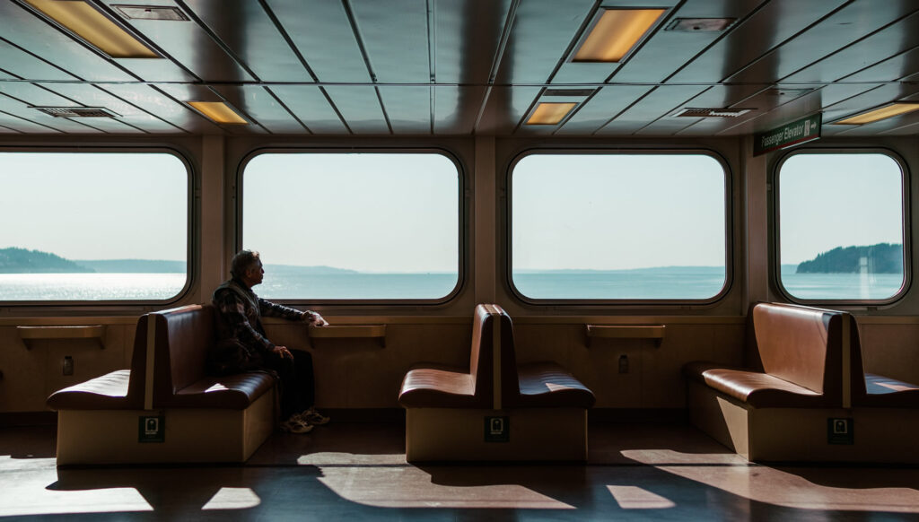 Imagen de una persona en un ferry, mirando por la ventana el mar.