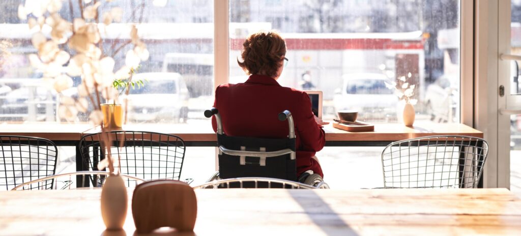 Mujer en silla de ruedas trabajando con un ordenador portátil.