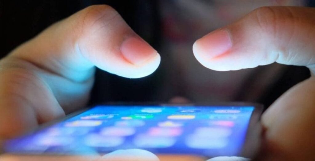 Manos de persona joven utilizando un teléfono móvil