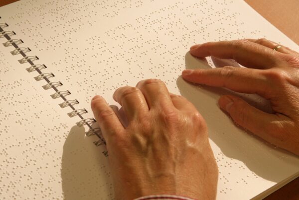Manos de hombre leyendo un texto en braille