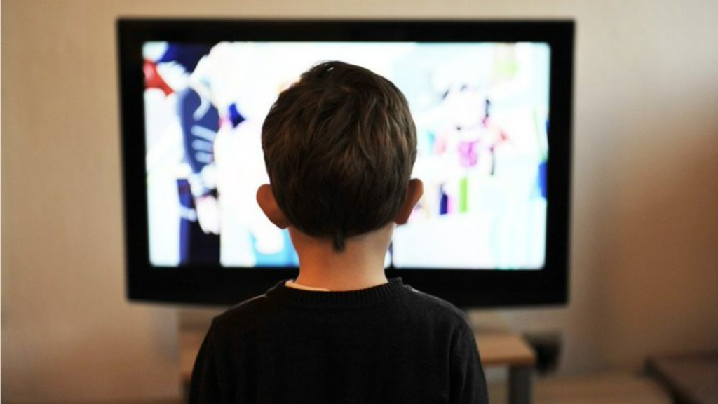 Niño de espaldas mirando una televisión encendida