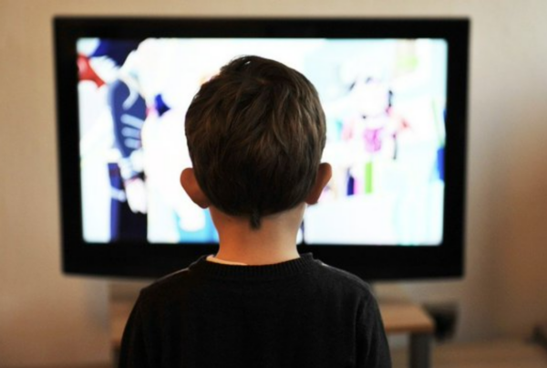 Niño de espaldas mirando una televisión encendida
