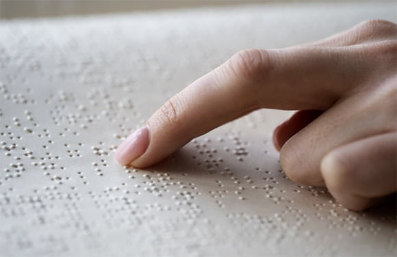 Mano de mujer leyendo un texto en braille