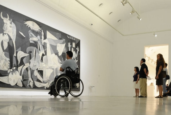 Joven en silla de ruedas contemplando un cuadro en un museo