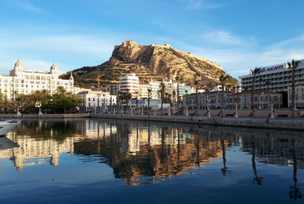 Fotografía de la ciudad de Alicante, con el mar, la línea de playa y el castillo al fondo