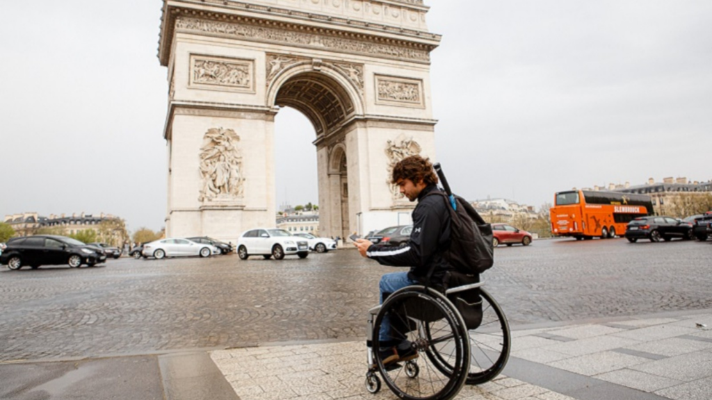 persona en silla de ruedas enfrente del arco del triunfo de parís
