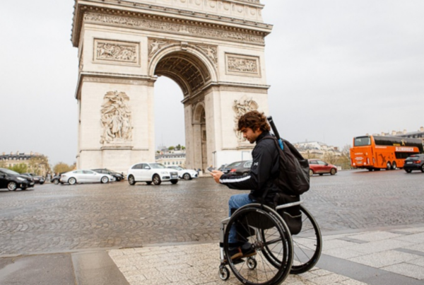 persona en silla de ruedas enfrente del arco del triunfo de parís