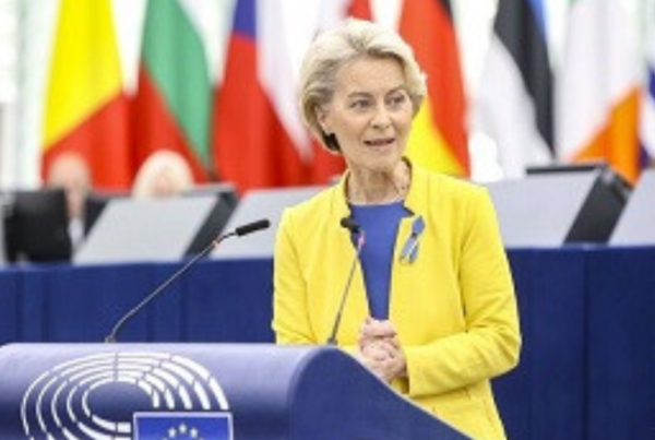 Fotografía de la presidenta de la Comisión Europea, Ursula Von der Leyen, en una comparecencia con las banderas de los países de fondo. Viste una chaqueta de color amarillo.
