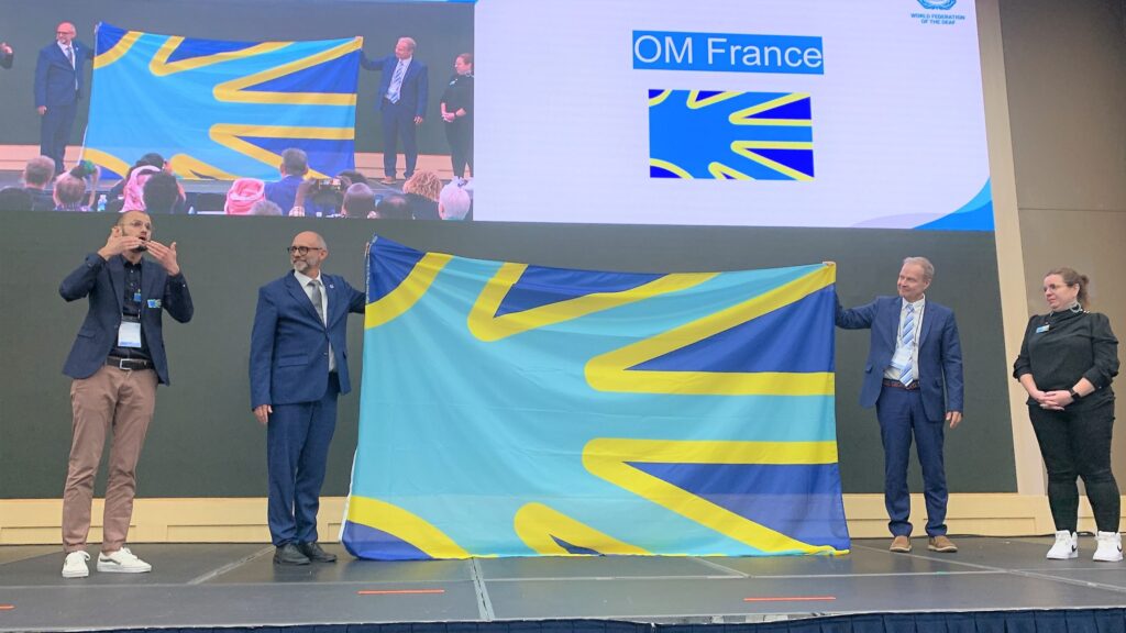 Presentación de la bandera de la federación mundial de sordos. La bandera está inspirada en una mano.
