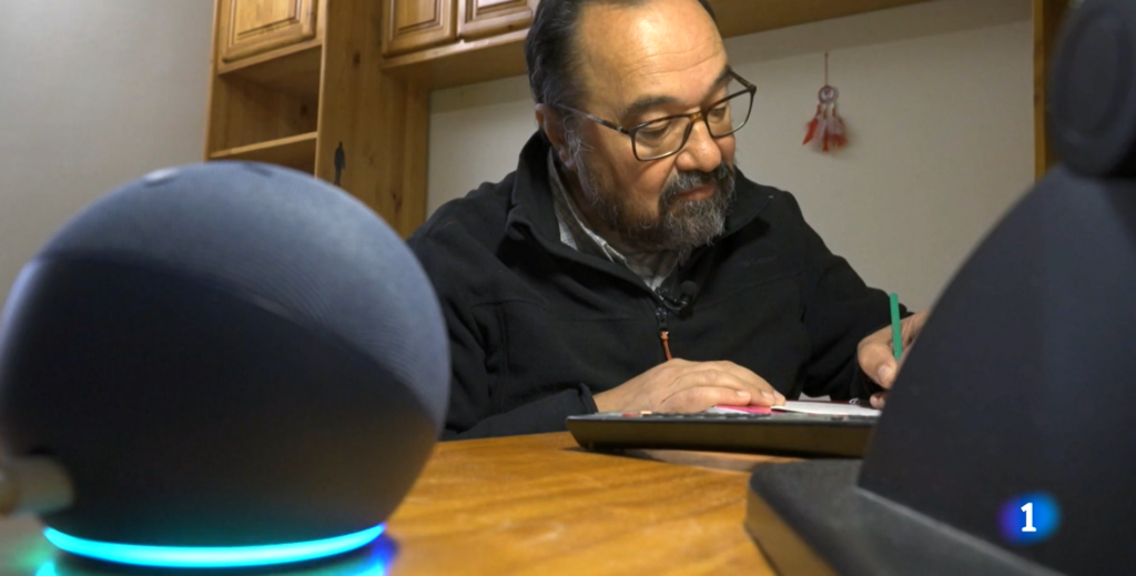 Dispositivo alexa en primer plano y un hombre con discapacidad escribiendo en su casa inteligente para salvar la brecha digital