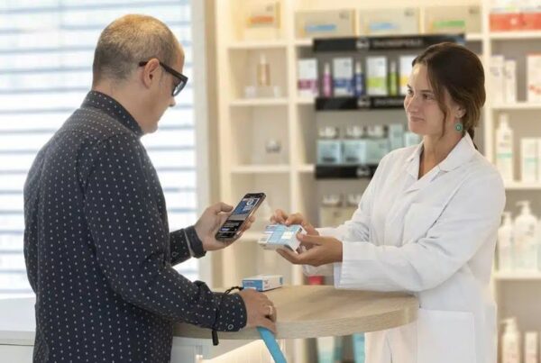 una farmacéutica entrega a un paciente con problemas de visión un medicamento. El hombre lee la información con el nuevo sistema de lectura con qr