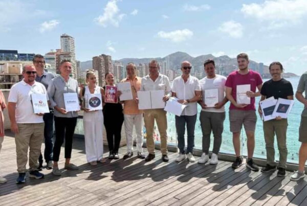 un grupo de hosteleros posa con sus cartas en braille, con la playa de fondo