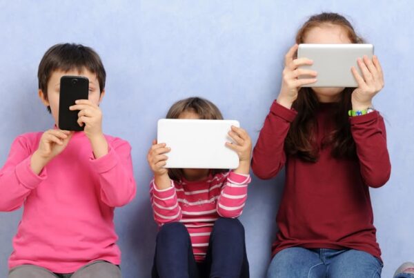 foto de tres niños, uno con un móvil y dos con dos tablets. Están mirando las pantallas, que tapan sus caras