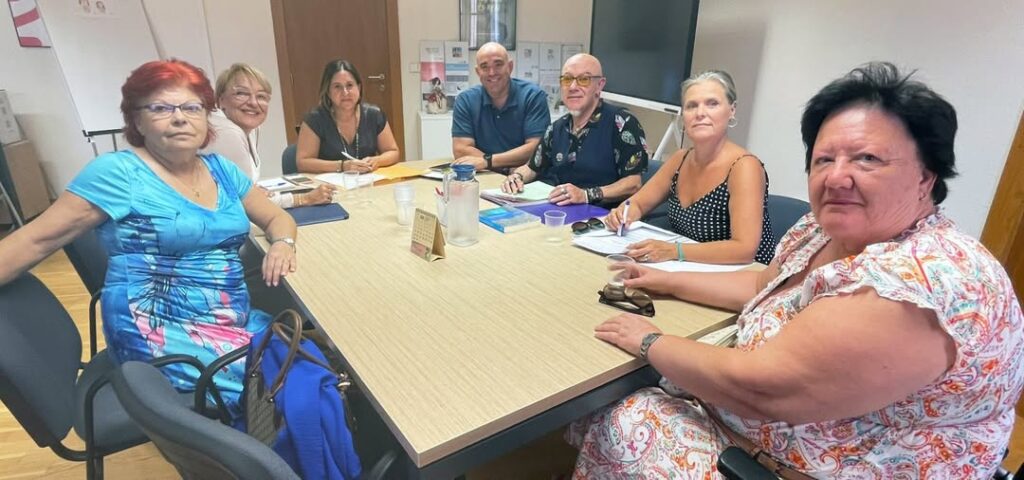 fotografía realizada durante la reunión de representantes del CERMI CV con representantes de la Conselleria de Eduación. Son siete personas, cinco mujeres y dos hombres, sentadas alrededor de una mesa de trabajo y mirando a la cámara.