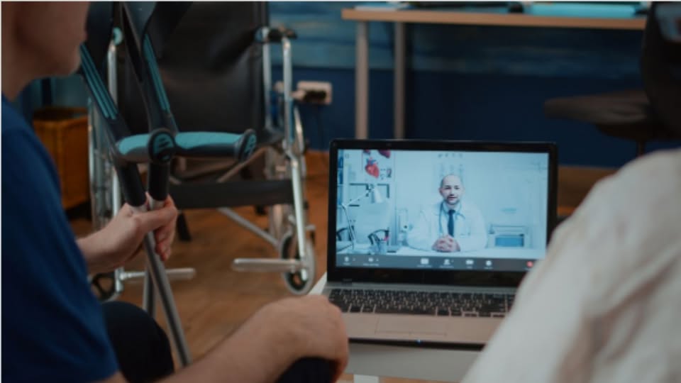 imagen de un ordenador portátil con un médico hablando con pacientes con discapacidad