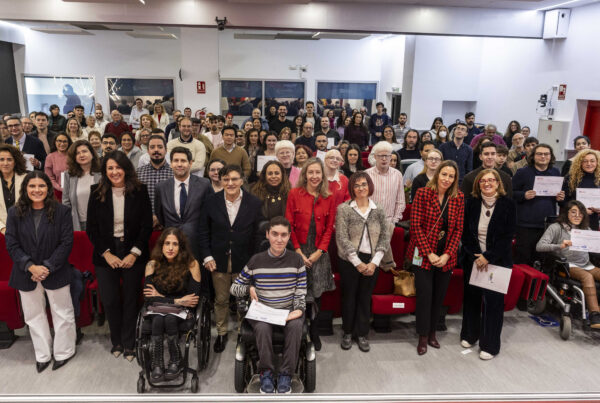fotografía de la sala con los participantes en el acto de entrega de las becas. Están todos mirando a la cámara.