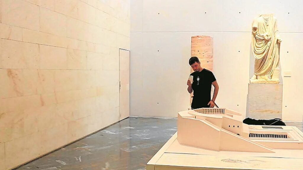 Persona observando maqueta arquitectónica en sala de exposiciones moderna, destacando la accesibilidad digital UPV y el enfoque en innovación y educación inclusiva.