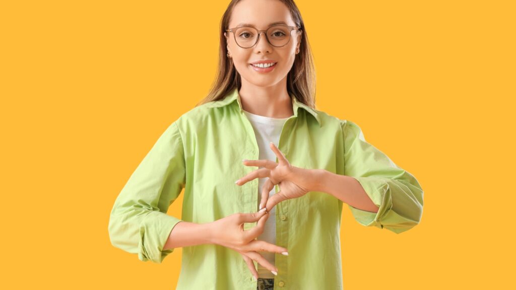 Mujer joven sonriente usando lengua de signos, ejemplificando accesibilidad digital UPV sobre fondo amarillo, destacando inclusión y comunicación accesible.