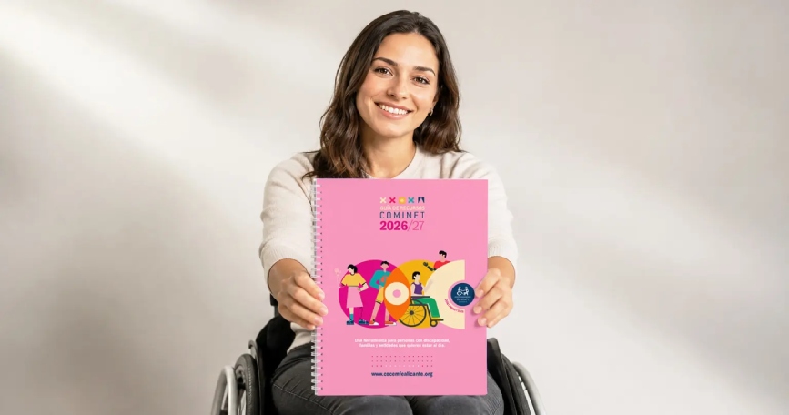 Una mujer joven en silla de ruedas enseña a cámara la portada de la guía
